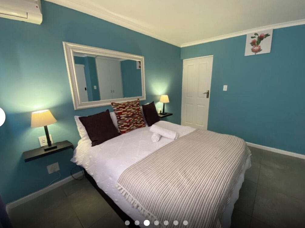 Una habitación de hotel con una cama, una mesita de noche con lámpara, un espejo y una puerta.