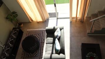 A living room with a sofa, a patterned rug, a coffee table, and a potted plant.