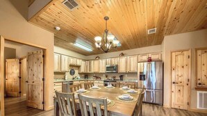 A spacious kitchen with wooden cabinets, a central island, and a dining area with chairs.