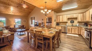 A spacious kitchen with wooden cabinets, a dining area with a round table, and a living room with a sofa and coffee table.