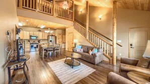 A spacious living area with a dining table, sofa, and a staircase leading to an upper level.