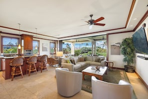 A spacious living area with a kitchen, dining area, and seating with a view of the outdoors.