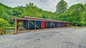 A row of cabins with a gravel driveway, set against a backdrop of dense green forest.