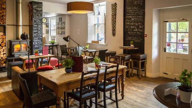 A cozy cafe with a wooden table and chairs, a chalkboard menu, and a rustic decor. - Woolpack Inn (Holmrook)