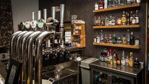 A bar area with multiple taps, shelves of liquor bottles, and a counter with glasses. - Woolpack Inn (Holmrook)