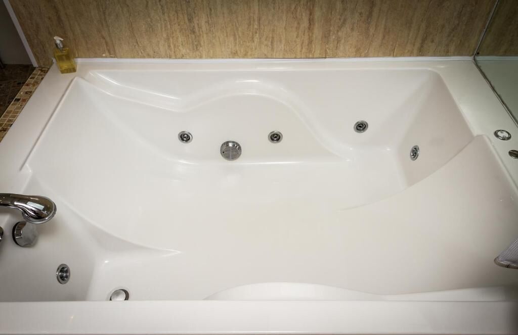 Une baignoire blanche dotée de plusieurs robinets et d’un drain.