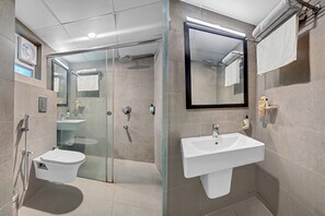 A modern bathroom with a glass-enclosed shower, a white sink, and a large mirror. - Treebo Hydotel Kompally (Hyderabad)