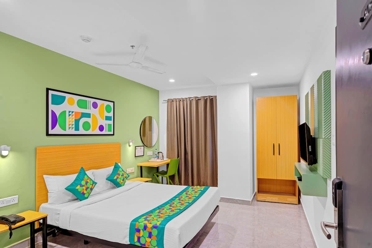 A hotel room with a bed, a desk, a chair, a wardrobe, and a television.
