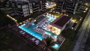 A modern hotel with a central swimming pool, multiple balconies, and outdoor seating areas.