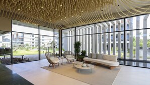 A spacious indoor area with large windows, a modern ceiling design, and a seating arrangement including a sofa and chairs.