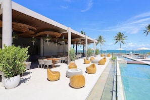 A poolside area with lounge chairs, a pool, and a view of the ocean. - Cais Ecoresidencia Luxo em Muro Alto (Ipojuca)
