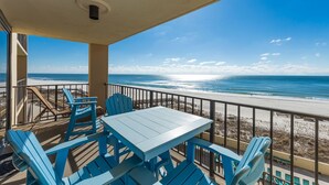 A balcony with a table and chairs overlooking a beach.