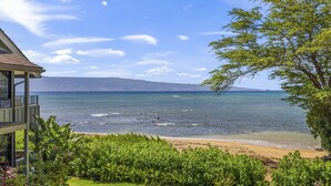 Ein Hotel direkt am Strand mit Blick auf das Meer und entfernte Berge.