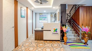 Ein Hotel-Empfangsbereich mit einer Rezeption, einer Treppe und einer Wand mit einem motivierenden Zitat.