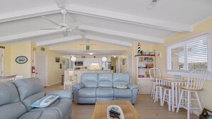 A living room with a sofa, a coffee table, and a dining area with chairs and a table. - Book A Key West Heart | Semi-Oceanfront Sandbridge Rental (Virginia Beach)