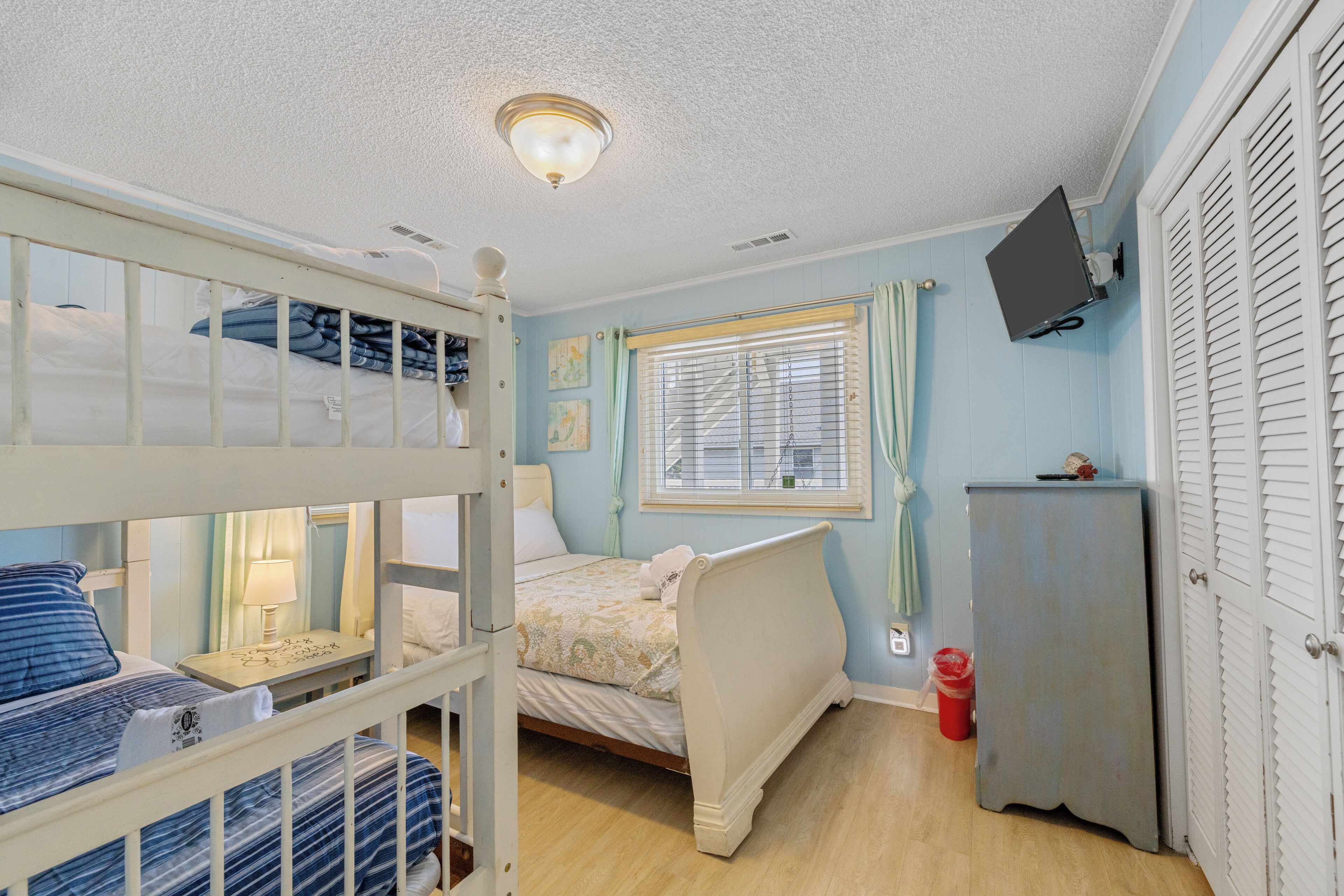 Ein Zimmer mit Etagenbetten, einem Schreibtisch, einem Bett, einem Fernseher und einem Kleiderschrank.