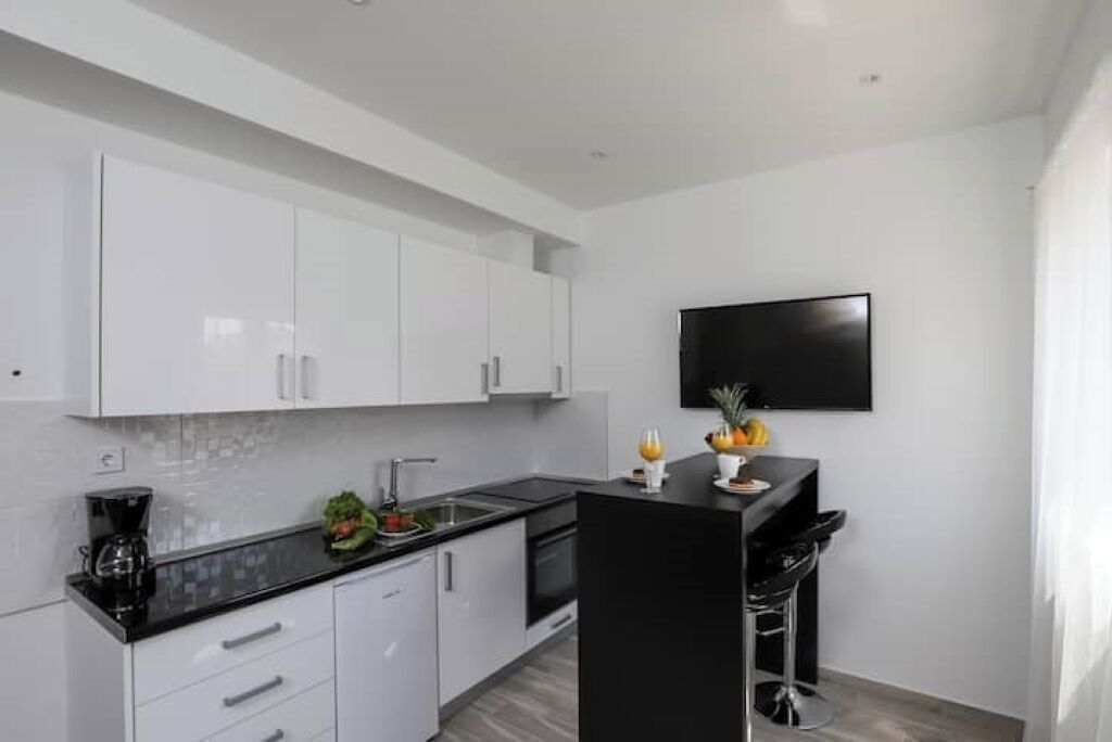 Una cocina moderna con armarios blancos, encimera negra y una isla negra con taburetes de bar.
