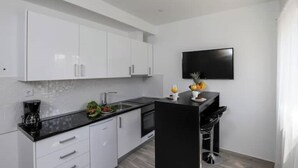 A modern kitchen with white cabinets, a black countertop, and a black island with bar stools.