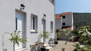A building with a paved courtyard, outdoor seating, and potted plants.