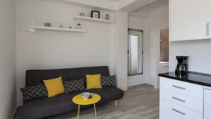 A modern living room with a dark sofa, yellow cushions, a small round table, and white cabinetry.