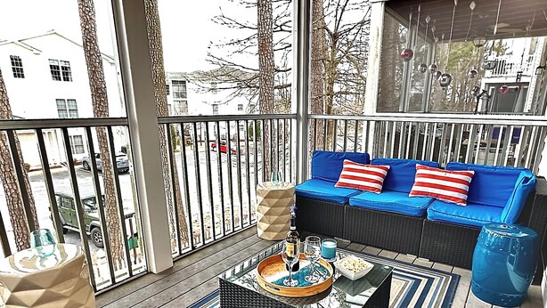 Un espace extérieur aménagé, abrité et doté d'un canapé en osier, de tapis à rayures et d'une table basse sur laquelle sont disposées des boissons et des en-cas.