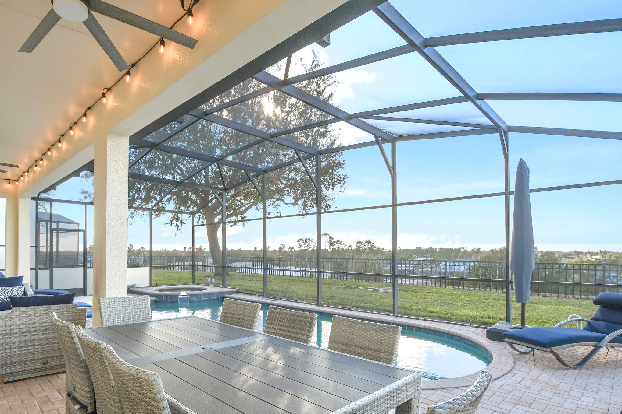 A covered outdoor area with a pool, seating, and a view of the surrounding landscape.
