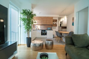 A modern living room with a sofa, a coffee table, and a large potted plant. - Apartment Wing 77 (Zadar)