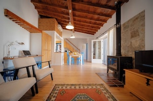Amplia sala de estar con techo de madera, televisor, chimenea y un comedor al fondo.