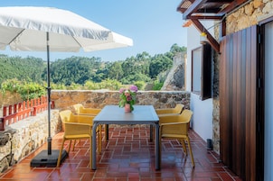 Un patio al aire libre con una mesa, sillas y un paraguas blanco.