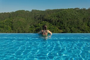 Una persona en una piscina con una colina boscosa al fondo.