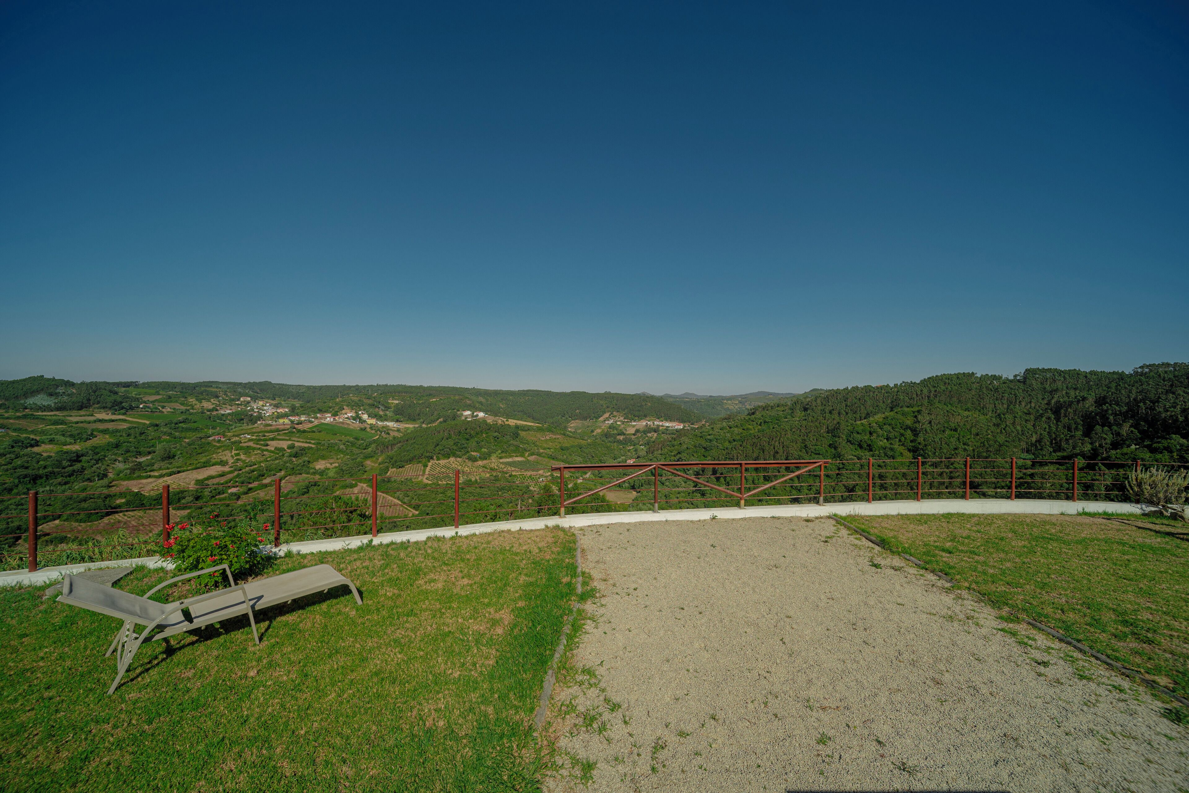 A grassy area with a gravel path, a metal fence, and a metal structure.
