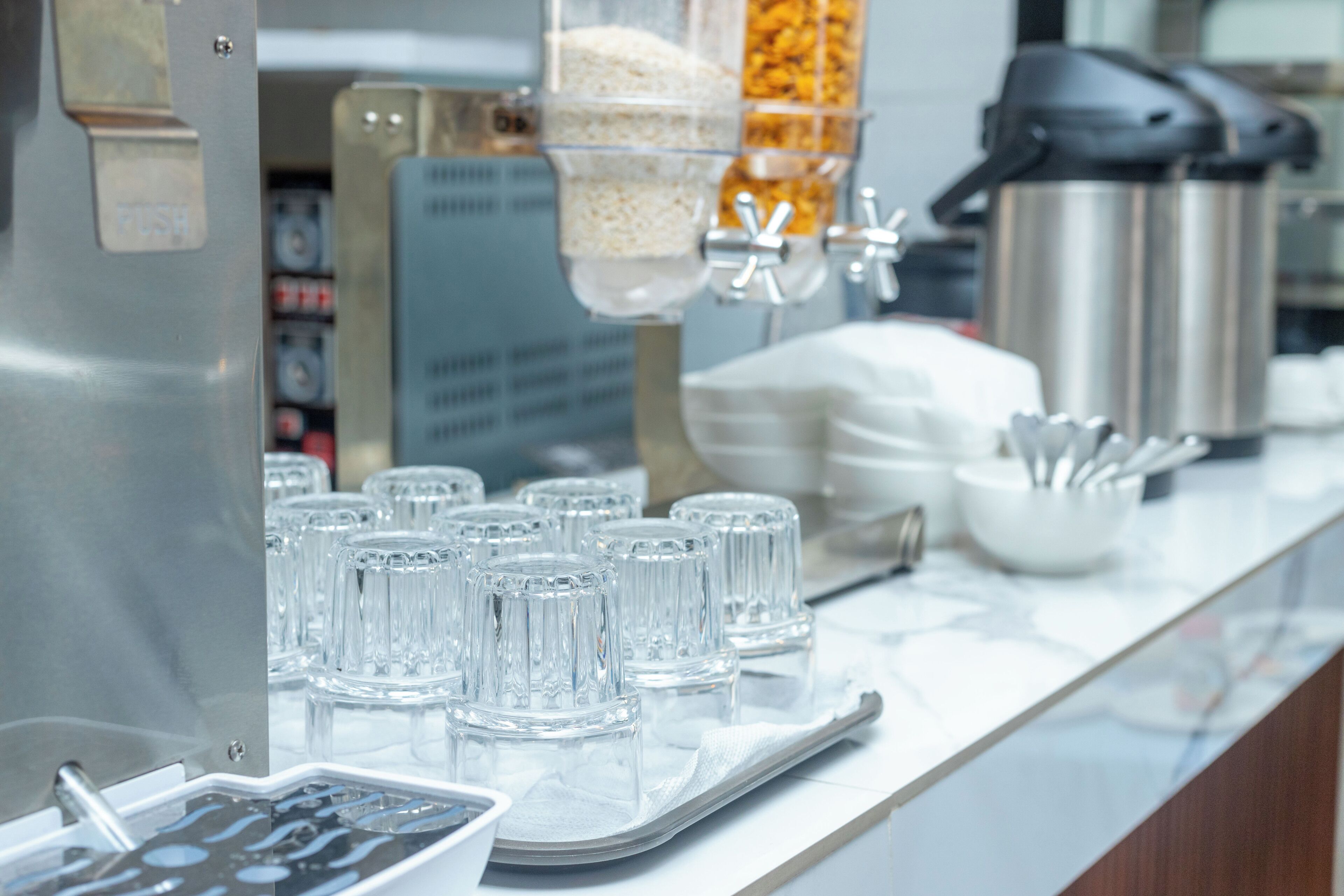 A breakfast bar with clear glasses, a coffee machine, and a rice dispenser.