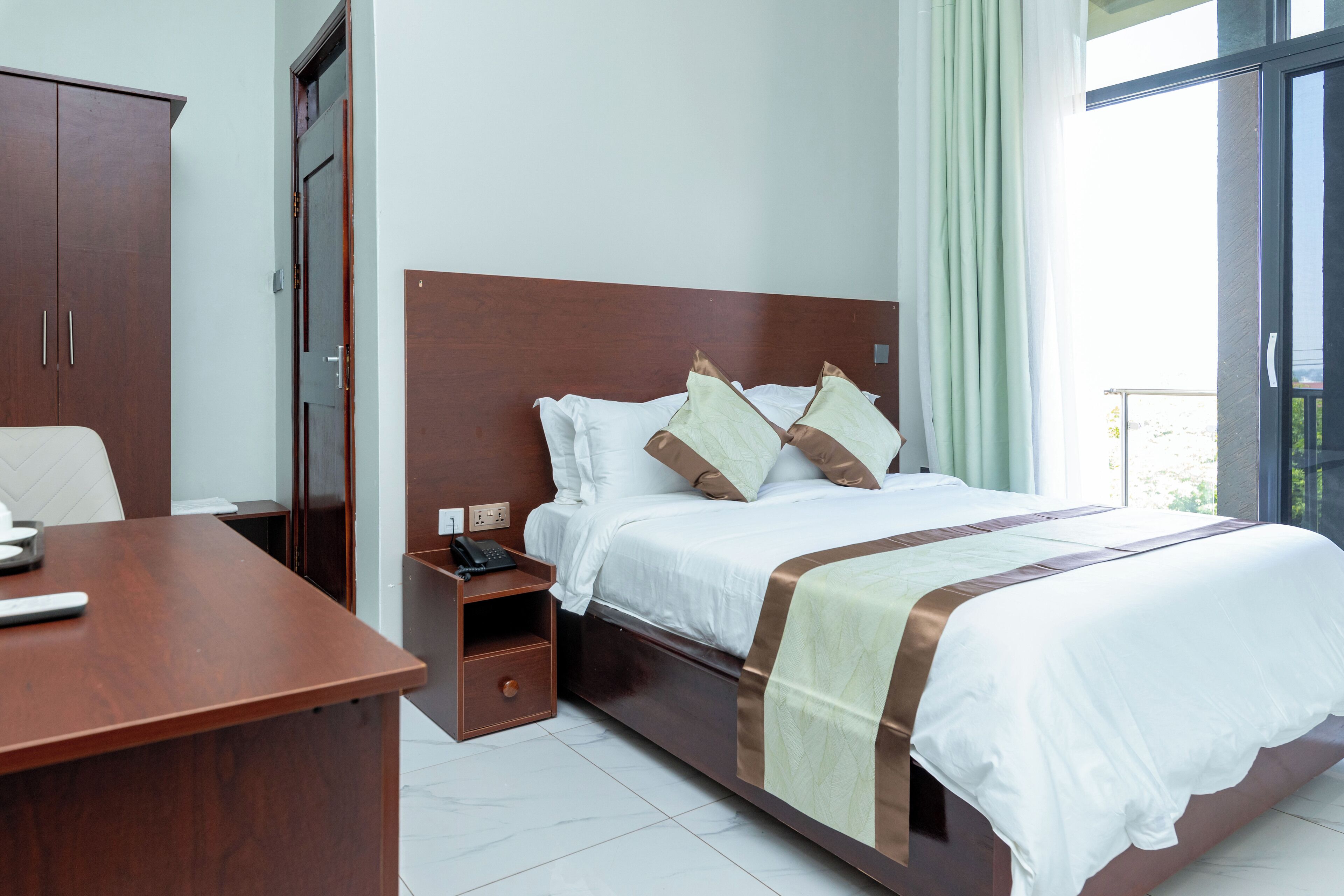 Una habitación de hotel con una cama de madera, un escritorio y un armario.