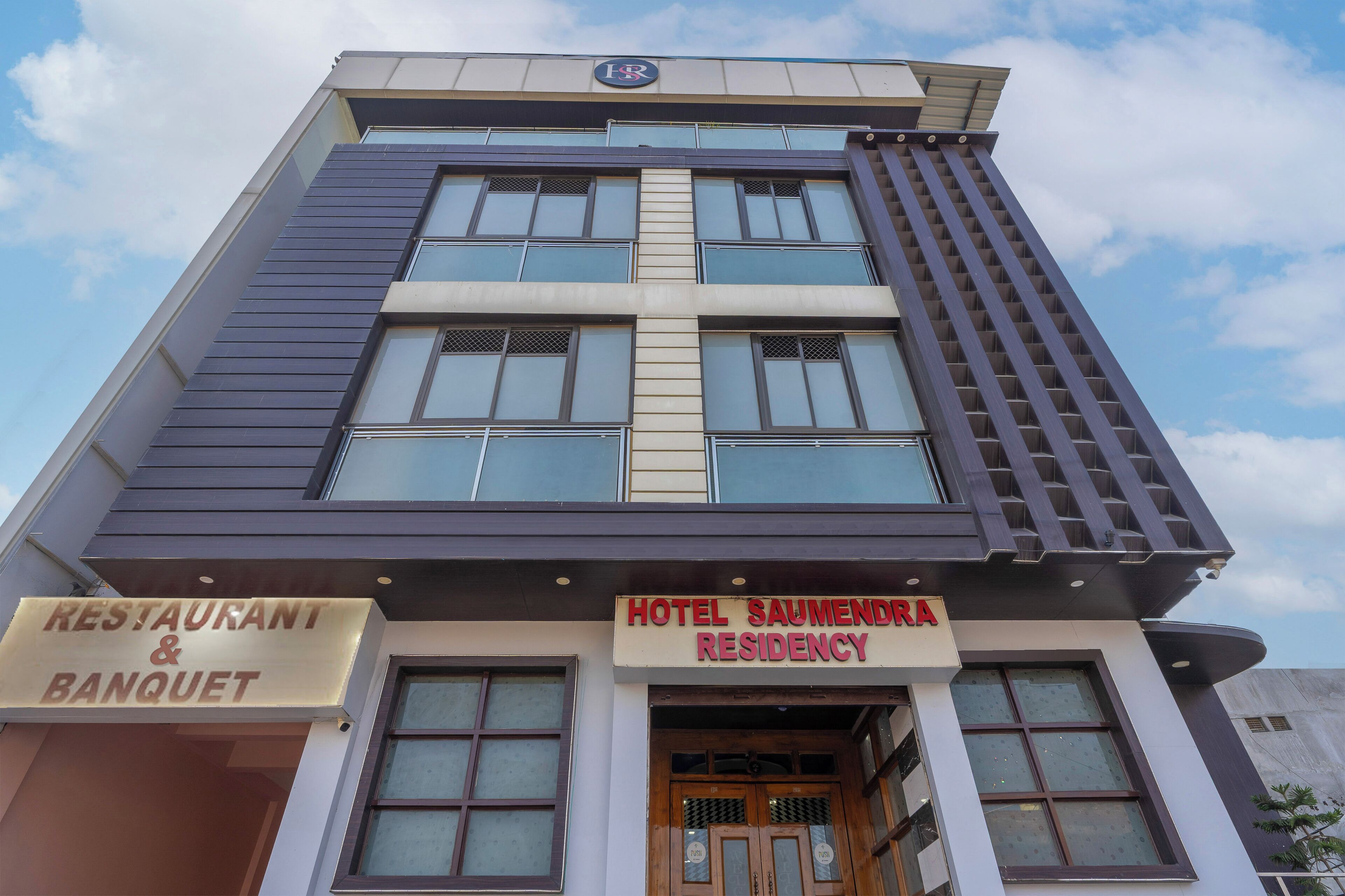 A hotel named 'HOTEL SAUMENDRA RESIDENCY' with a sign indicating a restaurant and banquet facility.