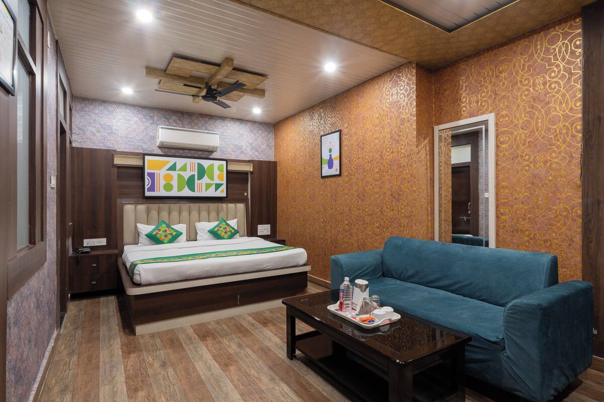 Una habitación de hotel con una cama, un sofá azul, una mesita de café y un ventilador de techo.