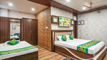 A hotel room with two beds, wooden flooring, a ceiling fan, and a decorative wall.