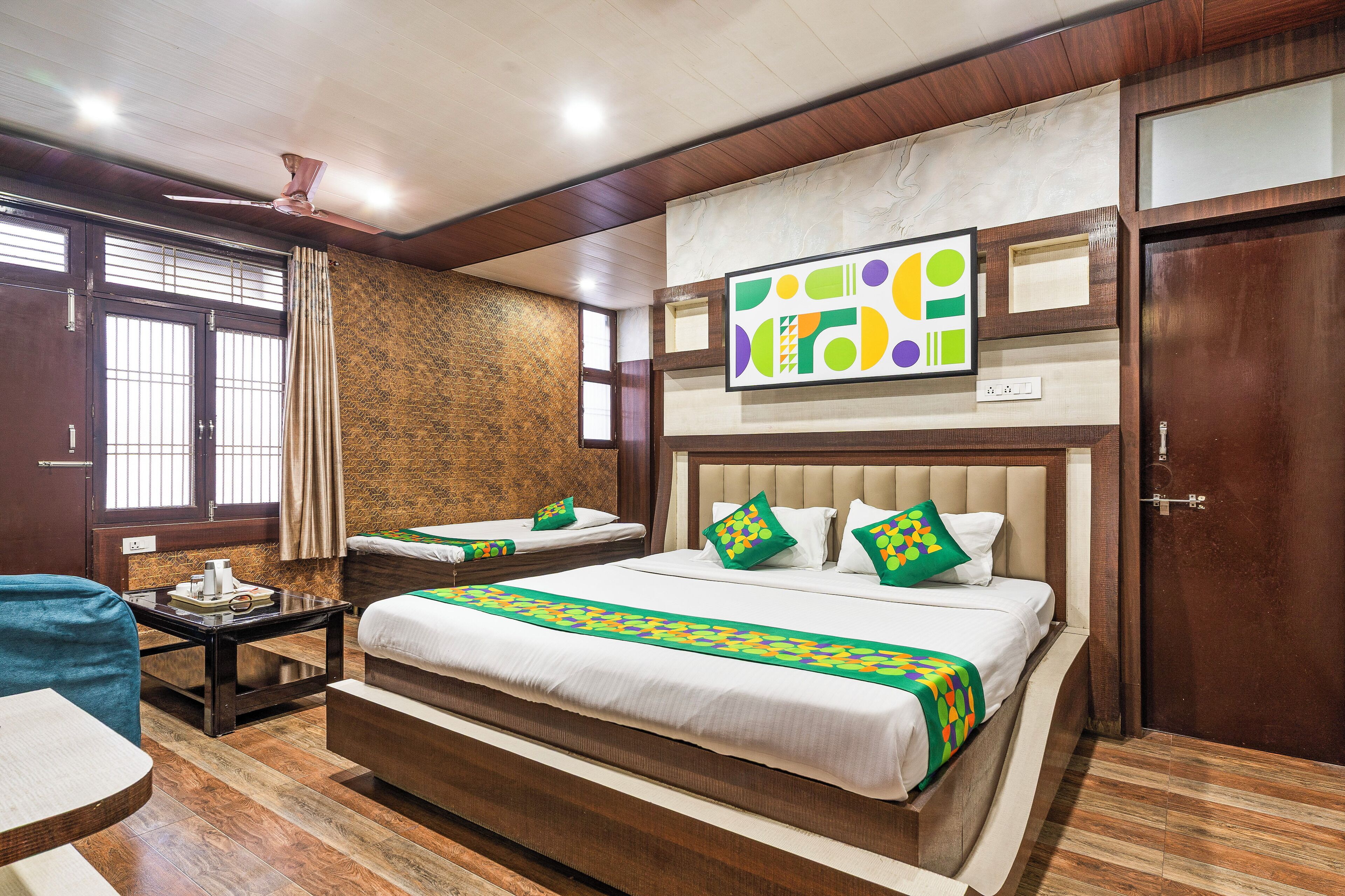 A hotel room with a large bed, a smaller bed, a desk, and a chair.