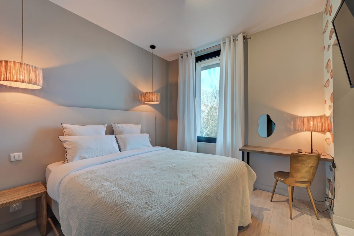 A bedroom with a bed, bedside tables, a desk, and a chair.
