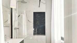 Een moderne badkamer met een marmeren wastafel, een douche en een raam.