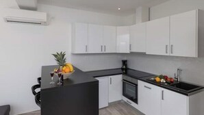 Una cocina moderna con armarios blancos, encimera negra y horno empotrado.