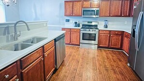 Une cuisine avec des meubles en bois, des appareils électroménagers en acier inoxydable et un lave-vaisselle.