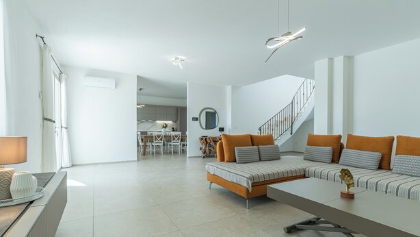 A modern living room with a sofa set, a dining area, and a staircase. - Villa Infinity with Pool by Wonderful Italy (Olbia)