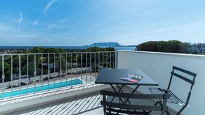 A balcony with a table and chairs, overlooking a swimming pool and a distant view of a mountain. - Villa Infinity with Pool by Wonderful Italy (Olbia)