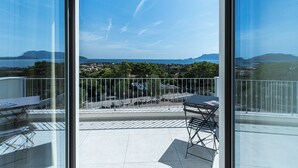 A balcony with a view of a coastal landscape, including a body of water and distant mountains. - Villa Infinity with Pool by Wonderful Italy (Olbia)