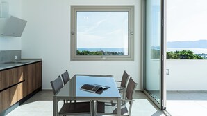 A modern kitchen with a dining area, a large window, and a view of the sea. - Villa Infinity with Pool by Wonderful Italy (Olbia)
