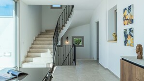 A modern interior with a staircase, a glass table, and artwork on the walls. - Villa Infinity with Pool by Wonderful Italy (Olbia)