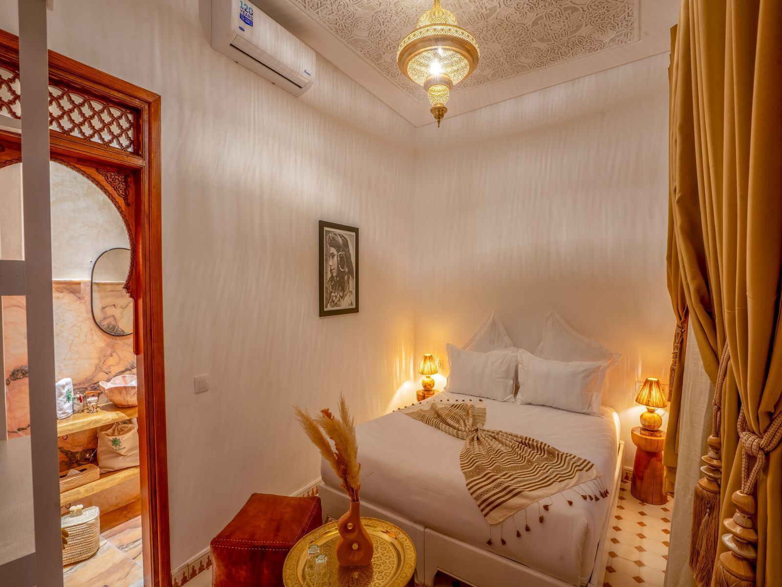 Un dormitorio con cama, lámparas de noche, un espejo decorativo y una araña.