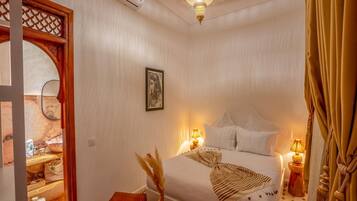 Un dormitorio con cama, lámparas de noche, un espejo decorativo y una araña.