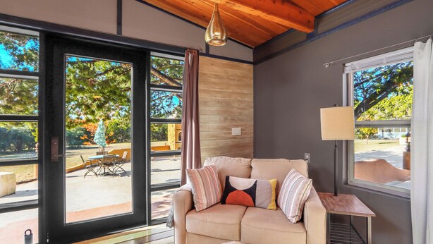 Una sala de estar moderna con un sofá color beige, una mesita auxiliar y un ventanal con cortinas.