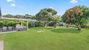 A backyard with a covered patio, outdoor furniture, and a lawn. - Mirrabooka - Charming 2-bedroom holiday house (Lake Cathie)